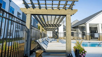 A wooden pergola over a hot tub in a backyard.